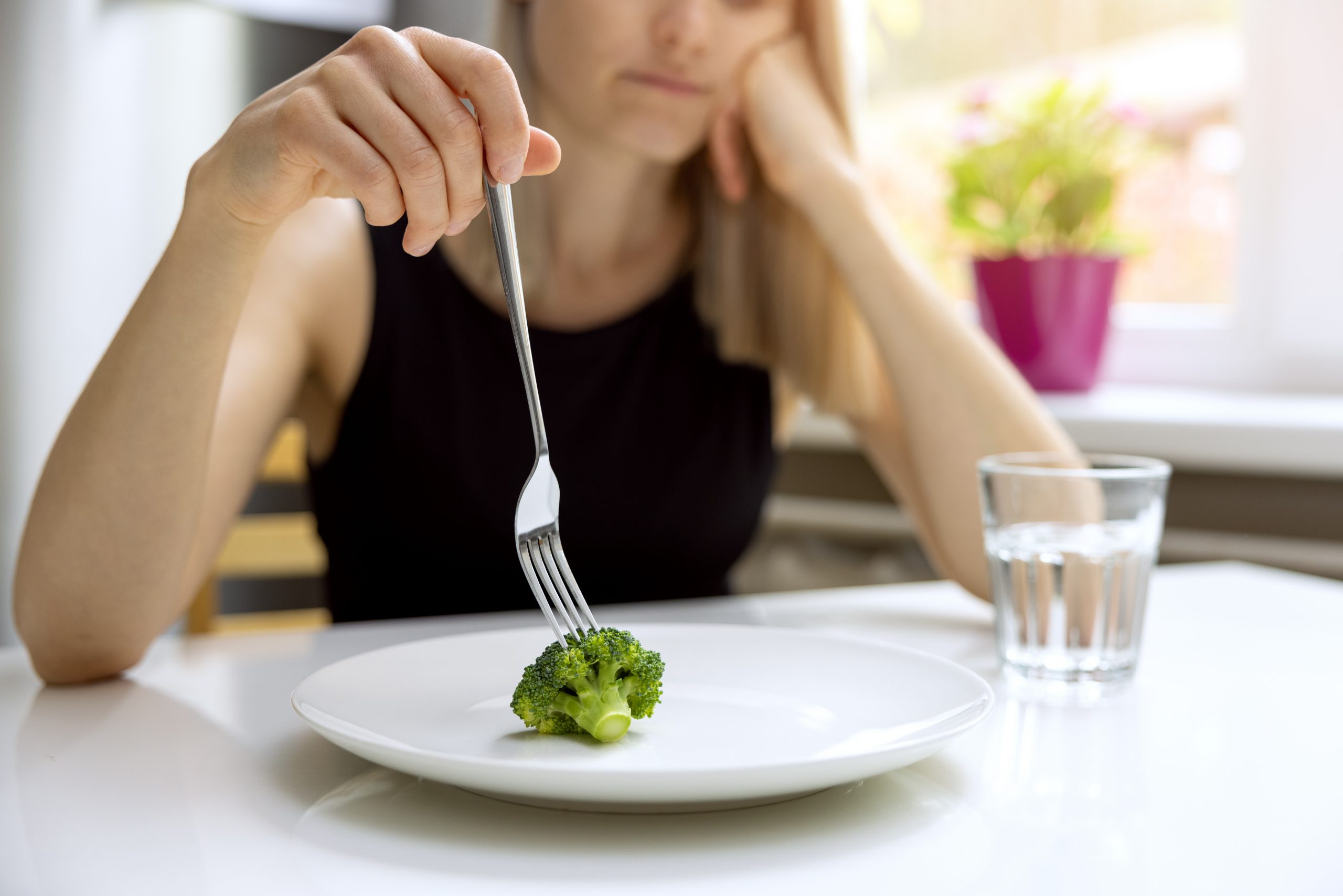 kobieta niechętnie patrzy na brokuła na talerzu