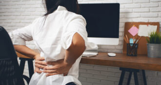 Kobieta biznesowa cierpiąca z powodu bólu pleców w biurze domowym.