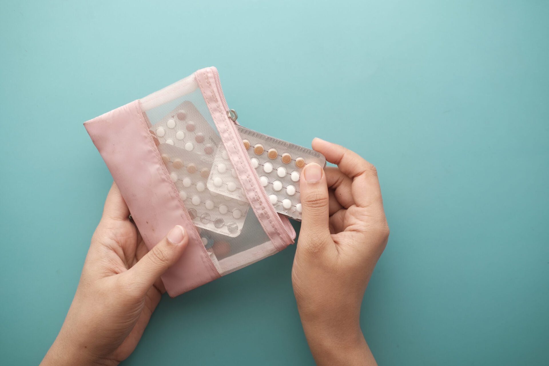 Ręka kobiety trzymającej tabletki antykoncepcyjne, zbliżenie.