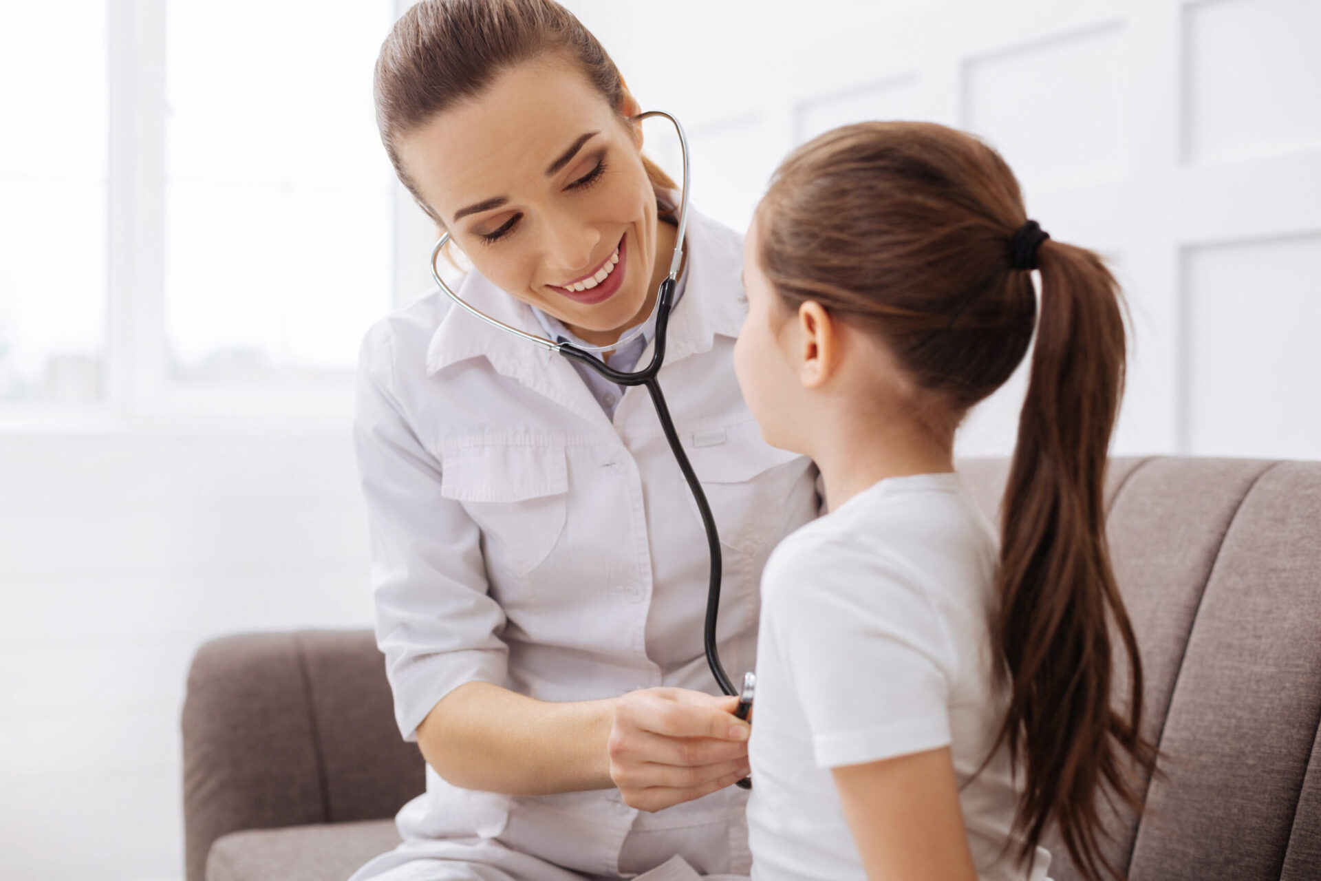 młoda lekarka bada stetoskopem małą dziewczynkę