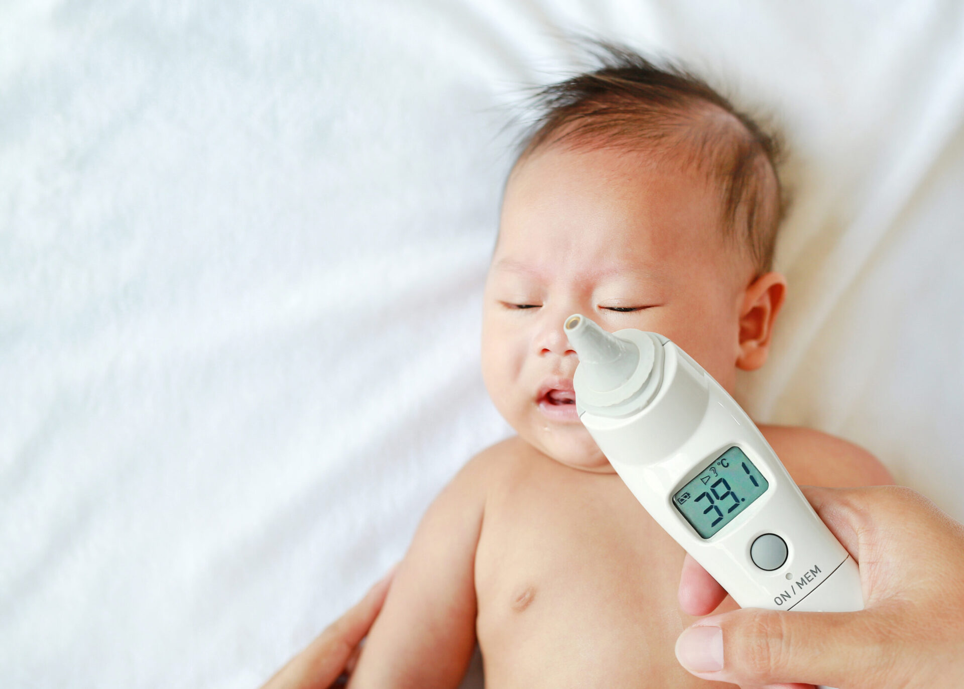 Matka mierzy temperaturę dla niemowlęcia termometrem usznym w domu.