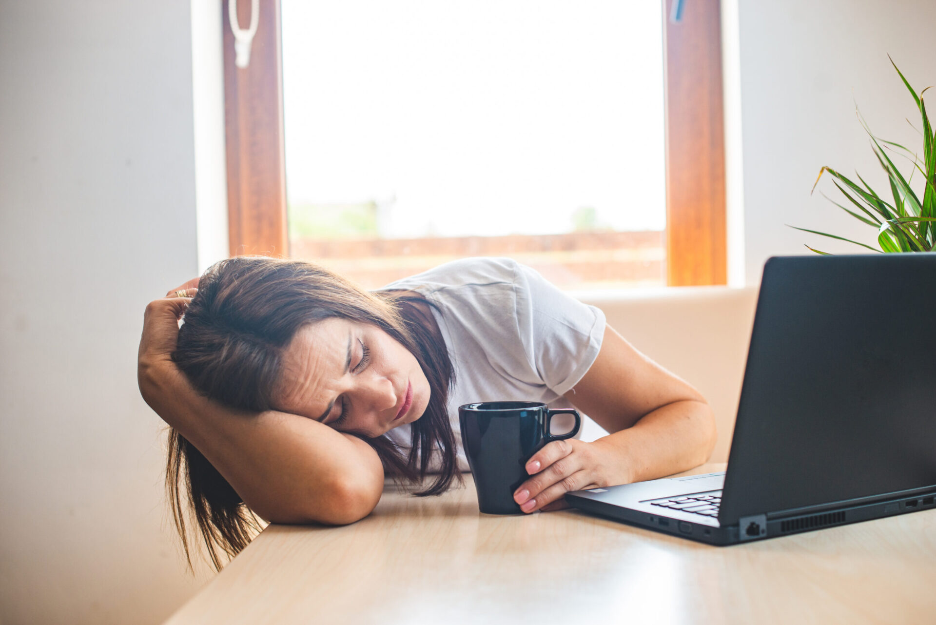 Zmęczona bizneswoman śpiąca na biurku w biurze. Młoda wyczerpana dziewczyna pracująca z domu. Kobieta korzystająca z laptopa. Przedsiębiorca, biznes, praca freelance, student, stres, koncepcja pracy z domu.